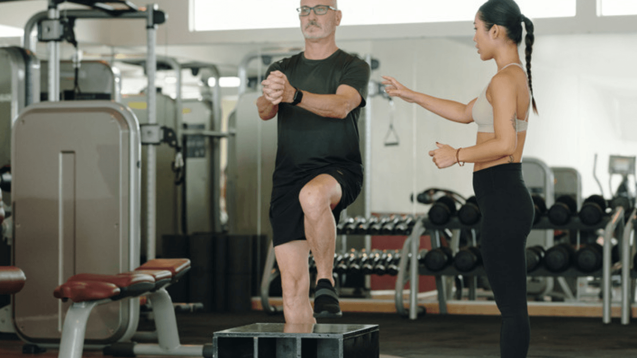 Man tränar steg-upp på låda med tränare i gym