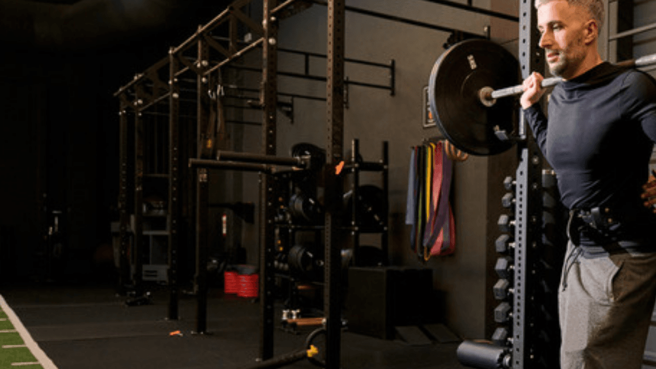 Man gör knäböj med skivstång i power rack