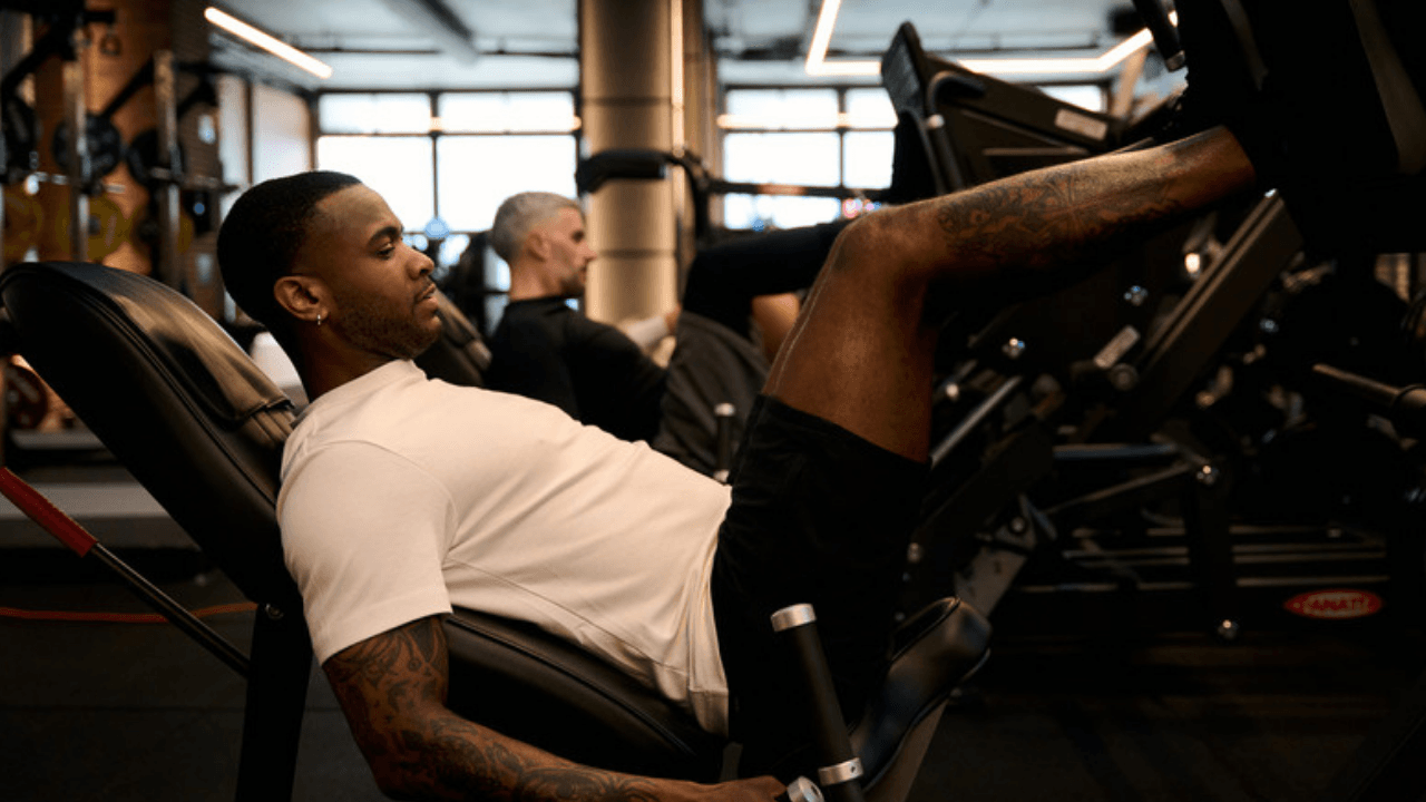 Man pressar ben i benpressmaskin på gym