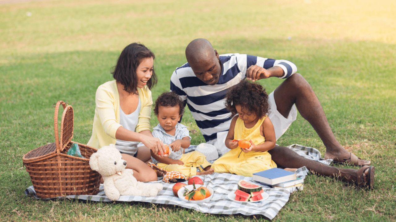 Familj med små barn på picknickfilt i park