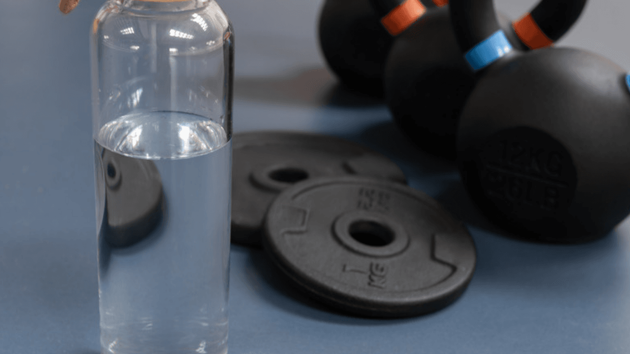 Kettlebell, viktskivor och vattenflaska på golv