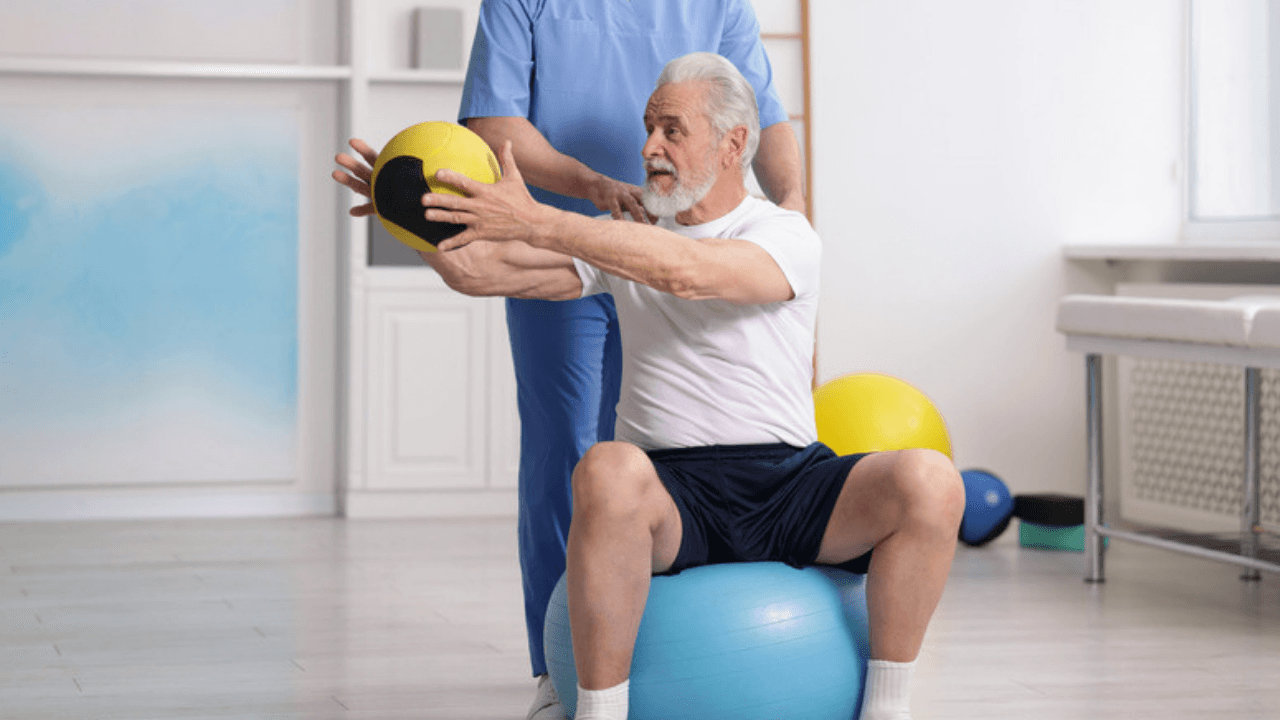 Man tränar på pilatesboll med stöd av fysioterapeut