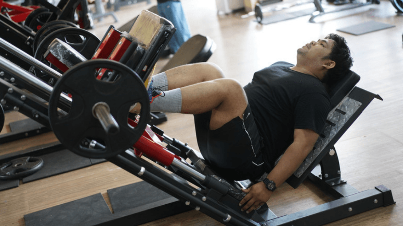 Person pressar vikten i vinklad benpressmaskin på gym – tung benträning för benen