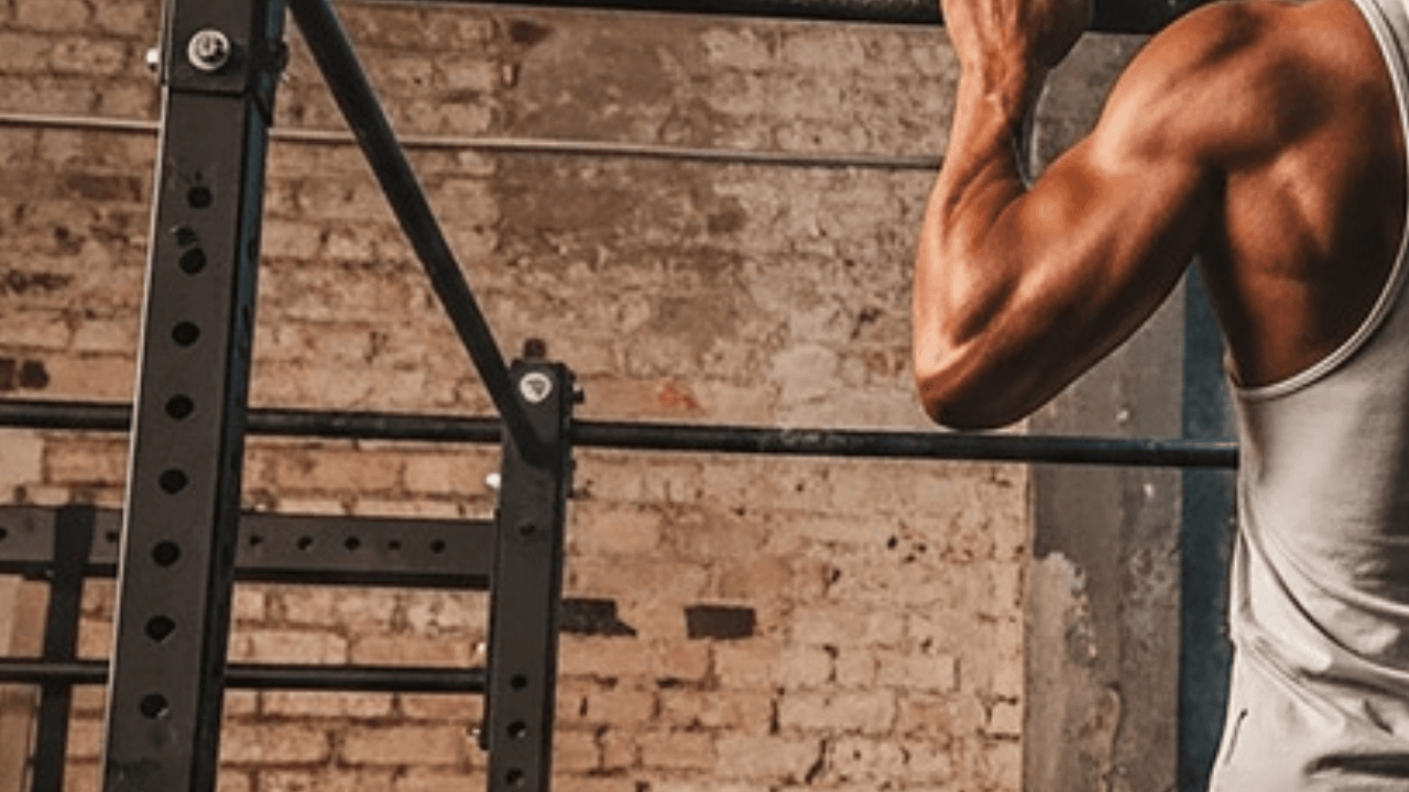 Person håller toppositionen på pull up-stång i gym – startläget för negativa pull ups