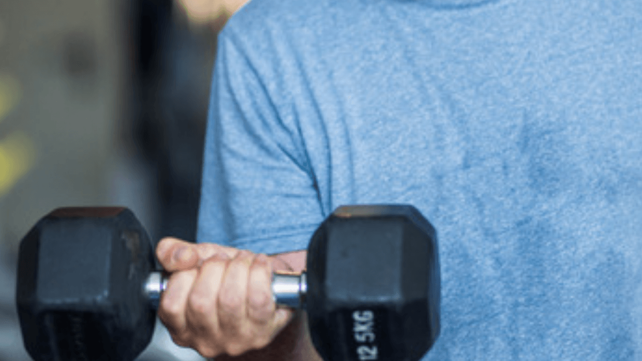Närbild på underarm och hand som håller hantel